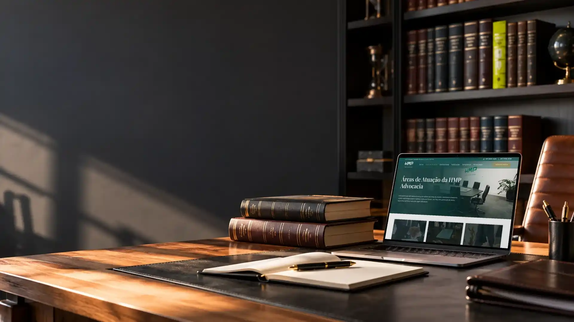 Mesa de um escritório de advocacia com livros de direito e o site do escritório aberto no notebook